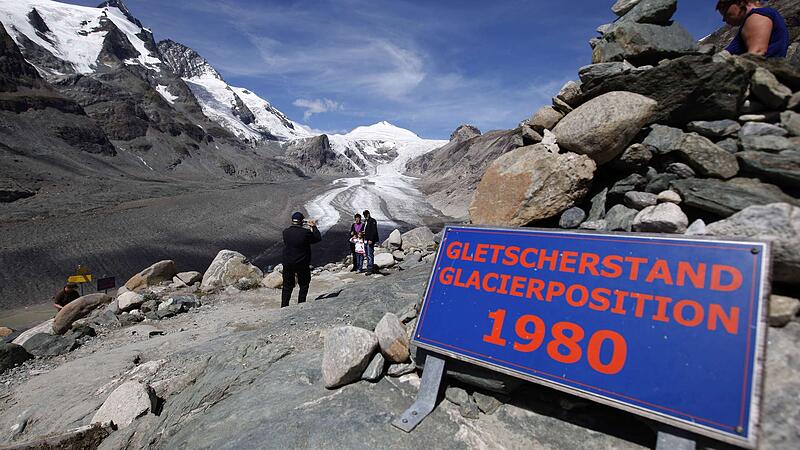 Tourists take photos in front of the Grossglockner summit and the Pasterze Glacier in the Austrian Province of Carinthia