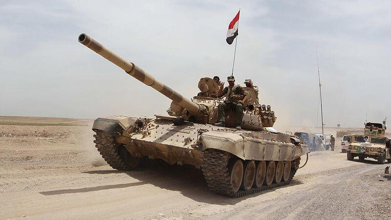 Shi'ite paramilitaries and iraqi army riding on a tank travel from Lake Tharthar towards Ramadi to fight against Islamic state militants, west of Samarra
