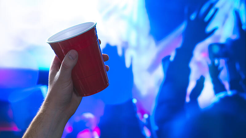Young man holding red party cup in nightclub dance floor