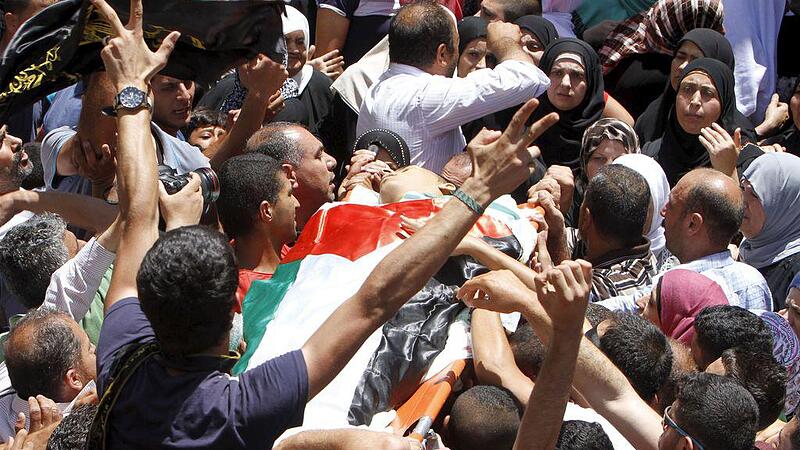Mourners carry the body of Palestinian man Mohammed Alawneh, 19, during his funeral in the West Bank village of Bruqin near Jenin