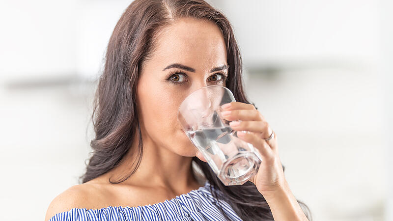 Woman rehydrates by drinking from a big glass of water.