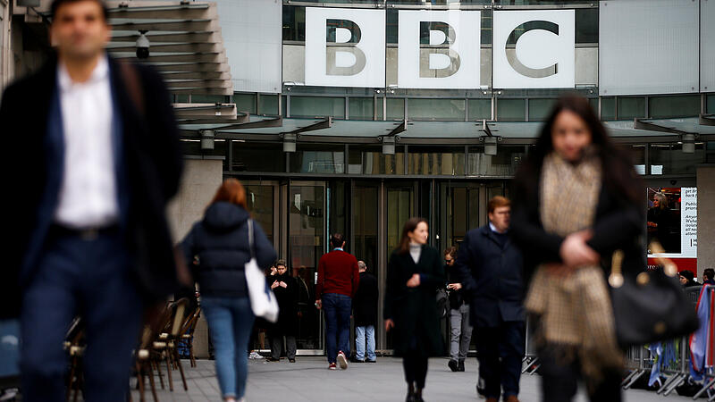 FILE PHOTO: Pedestrians walk past a BBC logo at Broadcasting House, as the corporation announced it will cut around 450 jobs from its news division, in London