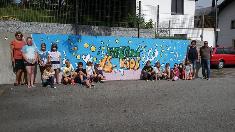 Kinder bemalten Betonmauer ihrer Volksschule