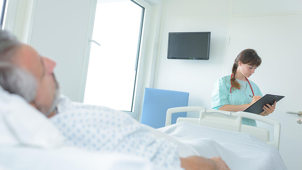 doctor taking notes from man patient lying in hospital bed
