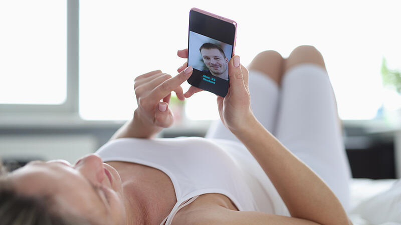 A woman lies on her back and looks into the phone