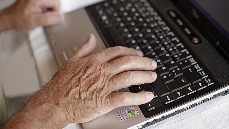 Alte Person arbeitet auf Laptop
