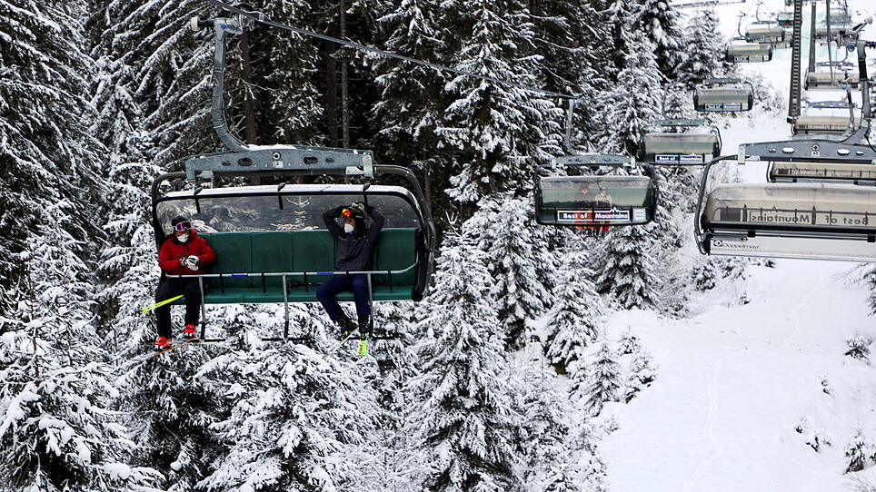 Skiers wear protective face masks on a chairlift in Flachau