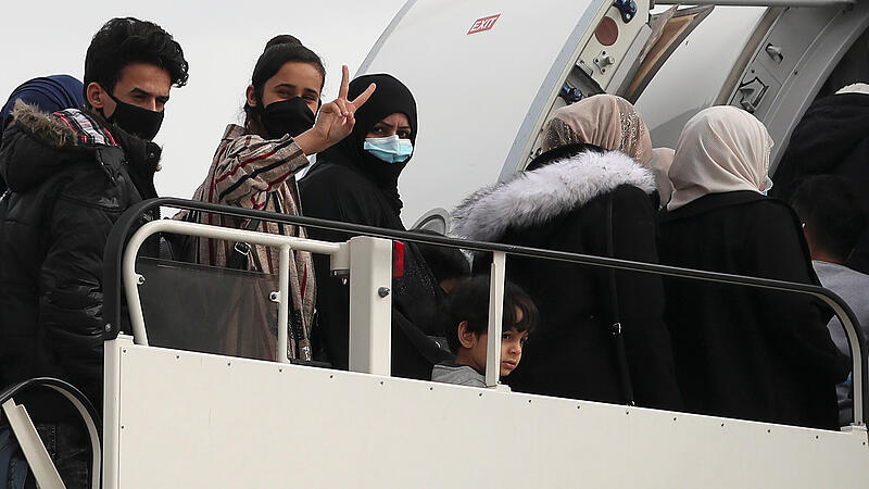 Refugees and migrants board their flight to Britain at the Athens International Airport