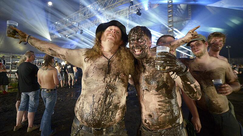 Heavy metal fans covered with mud pose for photographers during the 24th Wacken Open Air Festival in Wacken