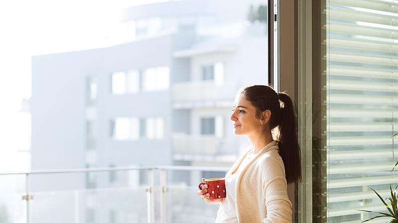 Woman relaxing on balcony holding cup of coffee or tea