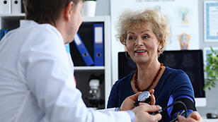 Male doctor measures pressure an elderly woman