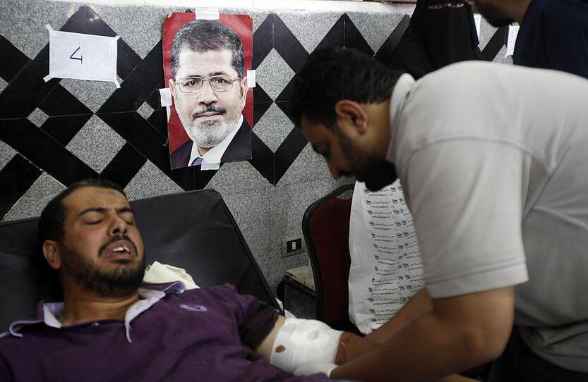 A supporter of Mursi reacts as he is treated by medicals after clashes near Republican Guard headquarters around the Raba El-Adwyia mosque square in Nasr City