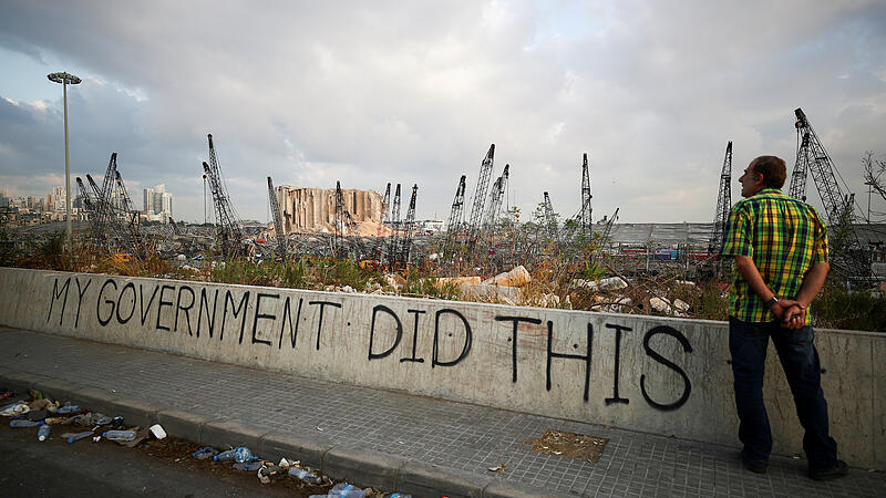 FILE PHOTO: A man stands next to graffiti at the damaged port area in the aftermath of a massive explosion in Beirut