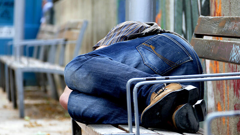 Mann schläft auf Parkbank