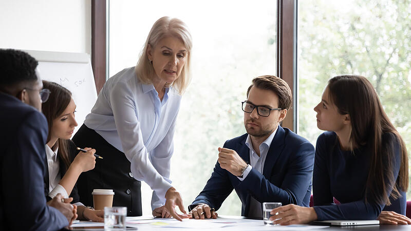 Mature business lady pointing colleagues to important place in documents