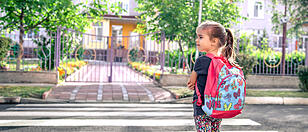 Children go to school, a happy student with a backpack, crosses the road