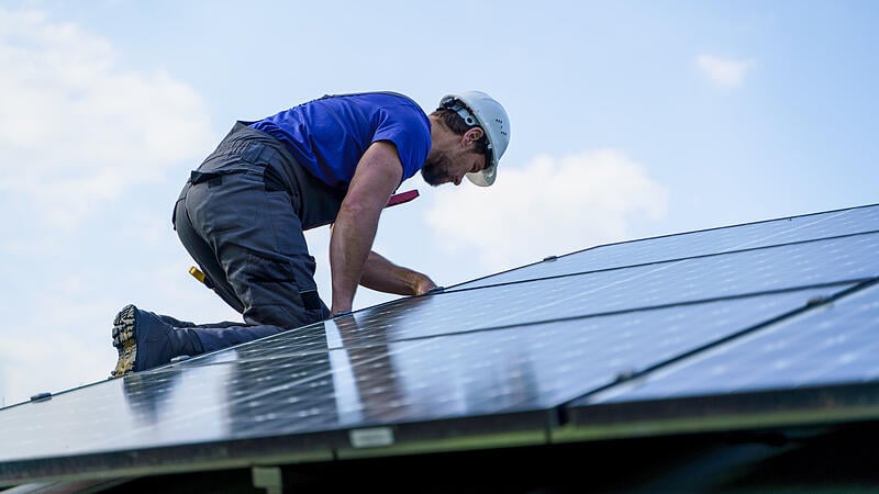 Man worker installing solar photovoltaic panels on roof, alternative energy concept.