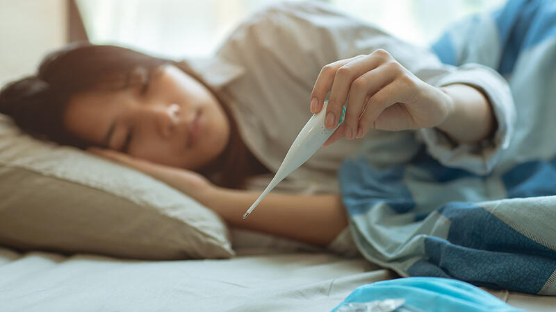 Asian teen infected with Covid-19 flu sick lying in bed due to a