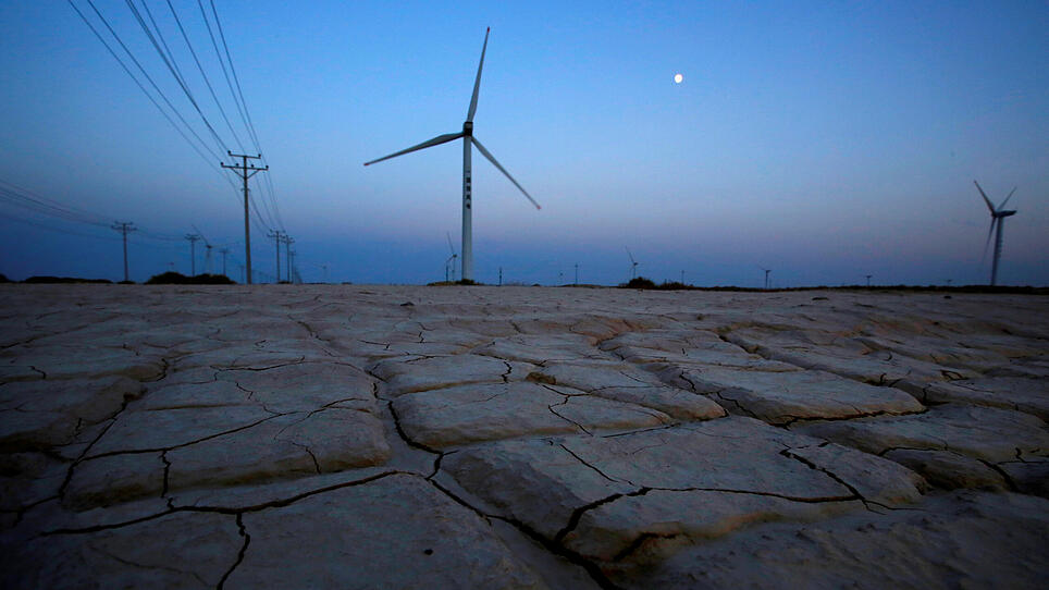 FILE PHOTO: Cracked earth marks a dried-up area near a wind turbine used to generate electricity at a wind farm in Guazhou, 950km (590 miles) northwest of Lanzhou, Gansu Province