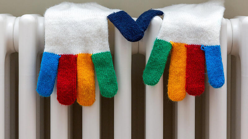 knitted gloves are dried on a white radiator