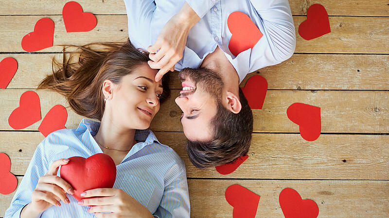 Couple lying on the wooden floor with hearts view from above.