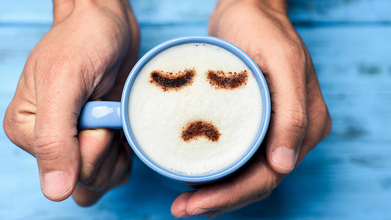 man with a cup of cappuccino with a sad face