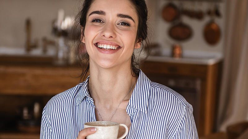 Photo of happy brunette woman drinking coffee while having break