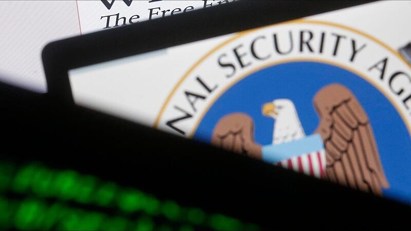A man is seen near cyber code and the U.S. National Security Agency logo in this photo illustration taken in Sarajevo