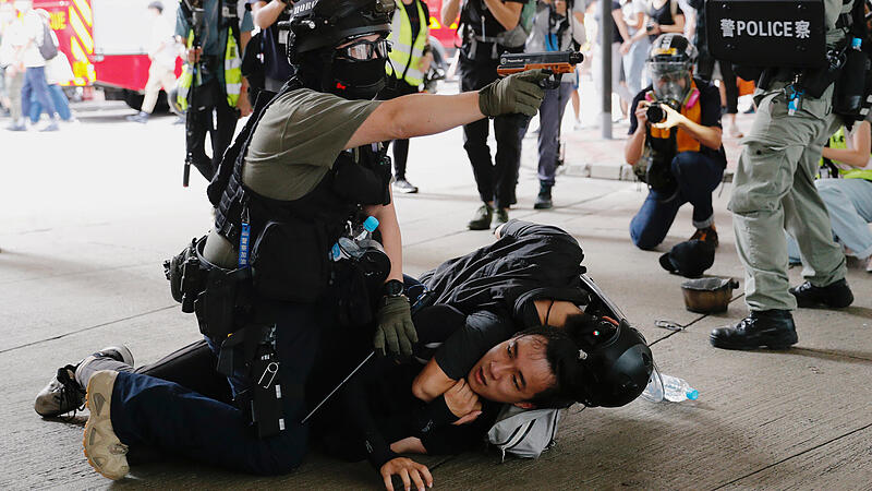 A police officer raises his pepper spray handgun as he detains a man during a march against the national security law at the anniversary of Hong Kong's handover to China from Britain in Hong Kong