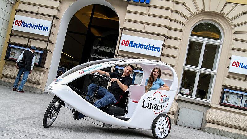 Stolze Linzer fahren mit der E-Rikscha der OÖNachrichten durch die City
