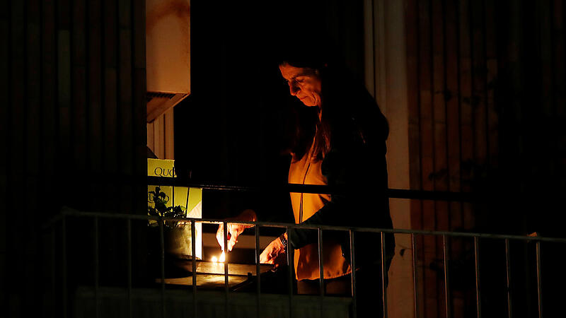 A woman lights a candle on her balcony as faithful across Italy say a prayer for people suffering from coronavirus disease (COVID-19)