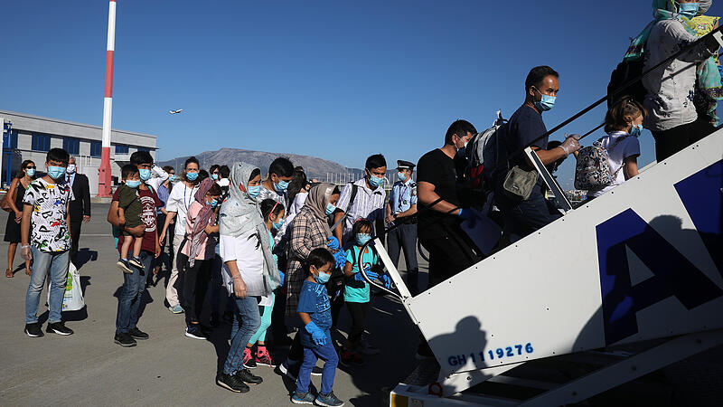 Refugees and migrants board an Aegean Airlines aircraft in Athens