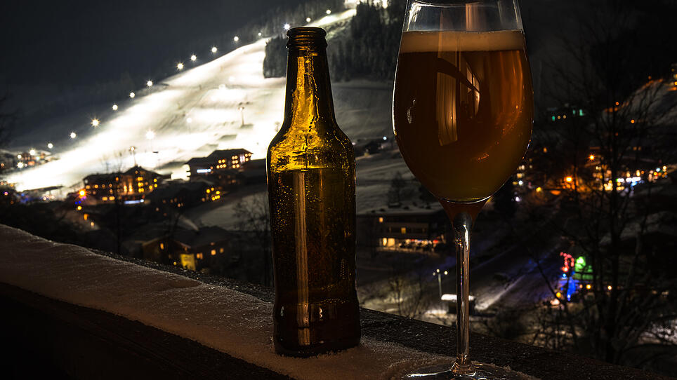 Glass and bottle with craft beer on a balcony at skiing village