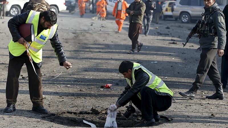 Afghan security forces investigate at the site of a suicide bomb attack in Kabul