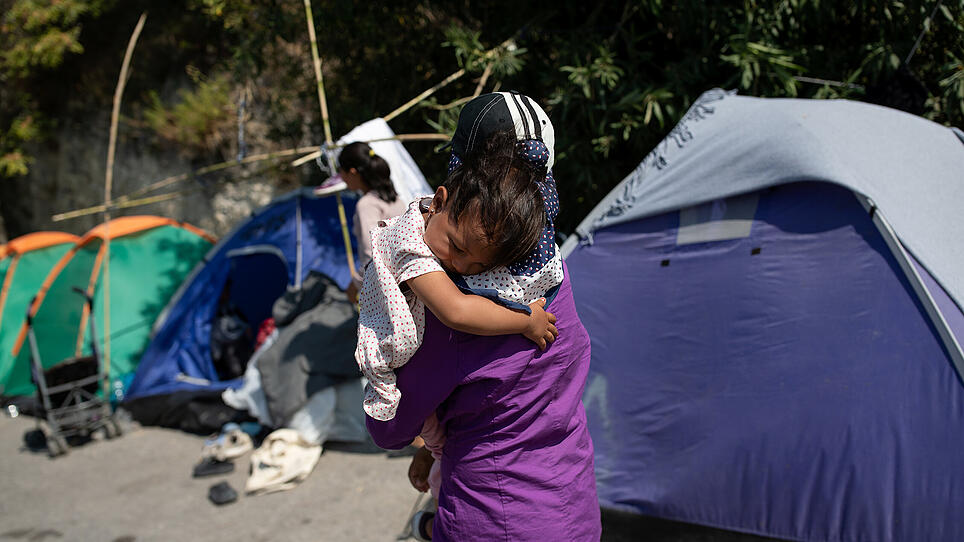 A migrant from the destroyed Moria camp holds a baby as refugees and migrants find shelter near a new temporary camp, on the island of Lesbos